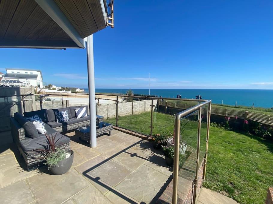 a patio with a couch and a view of the ocean at Cliff Top Heights-Beach front house near Brighton in Rottingdean