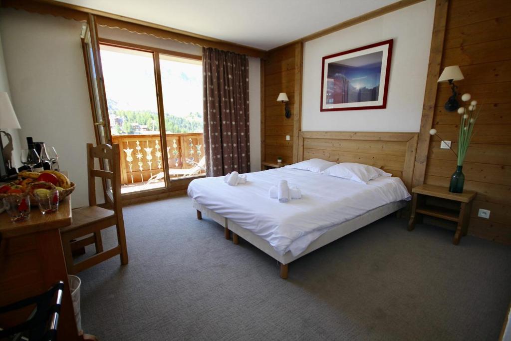 a bedroom with a large white bed and a balcony at Le Vancouver in La Plagne