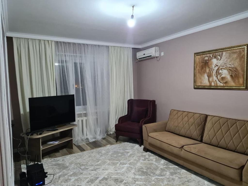 a living room with a couch and a television at Avtovokzal 3 Room apt in Qyzylorda