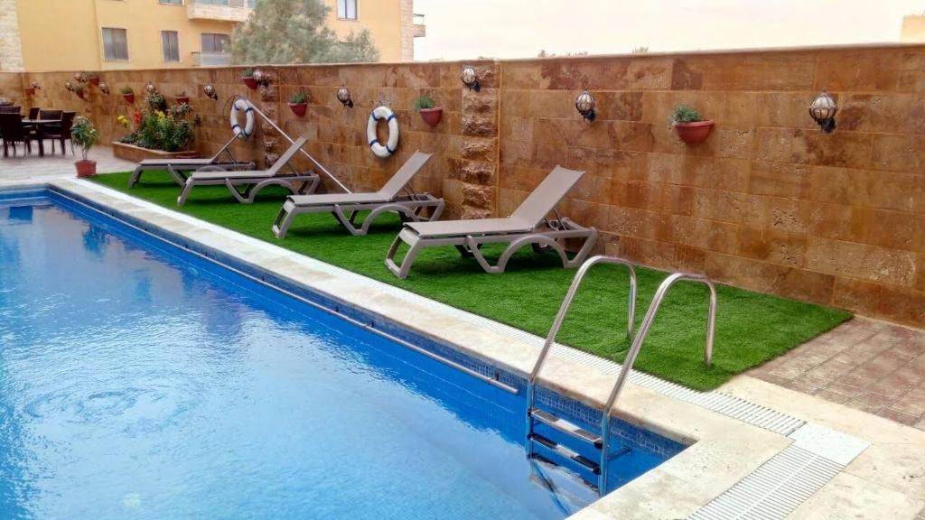 索瓦馬的住宿－مشروع ميريت البحر الميت السكني العائلي，一个带躺椅的游泳池,位于墙上