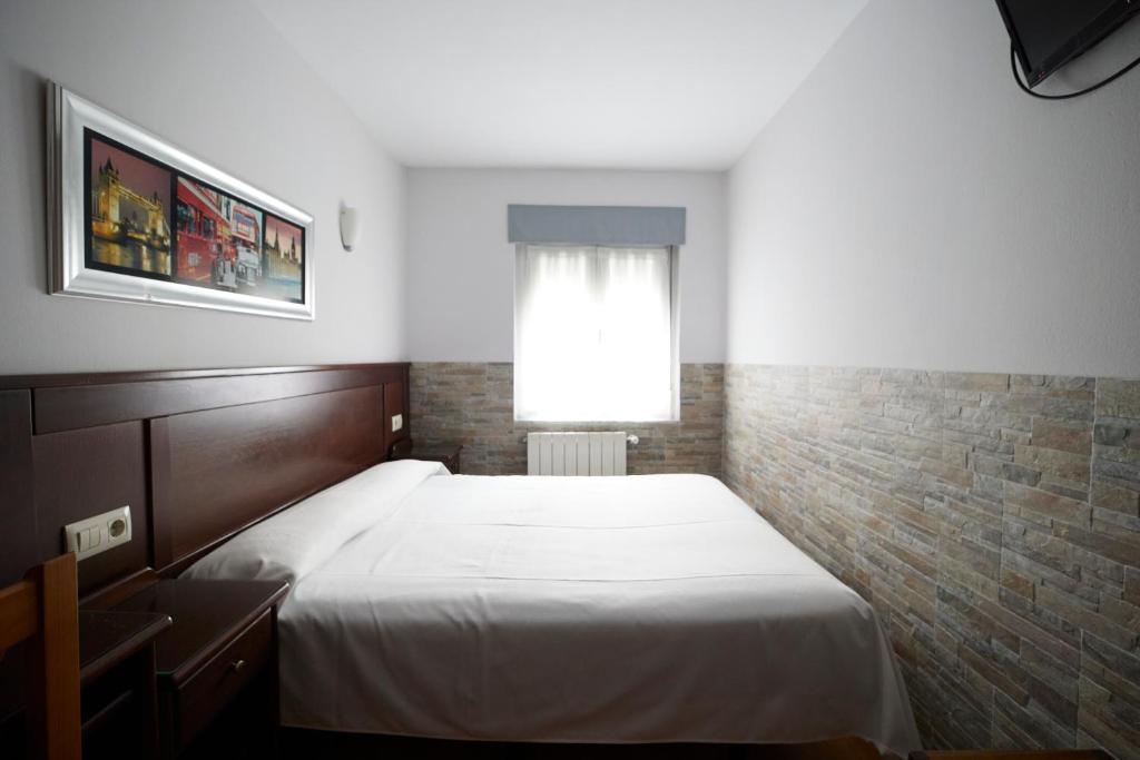 um quarto com uma cama branca e uma janela em Pensión Serafín em Avilés