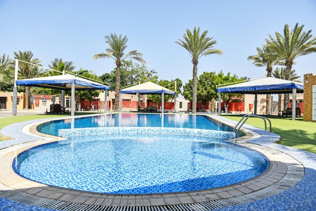 a swimming pool at a resort with blue umbrellas at OYO 138 Gulf Sand Motel in Barka