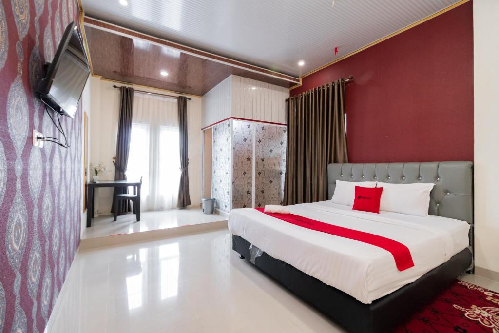 a bedroom with a large bed with a red wall at RedDoorz Syariah near Minangkabau International Aiport in Duku