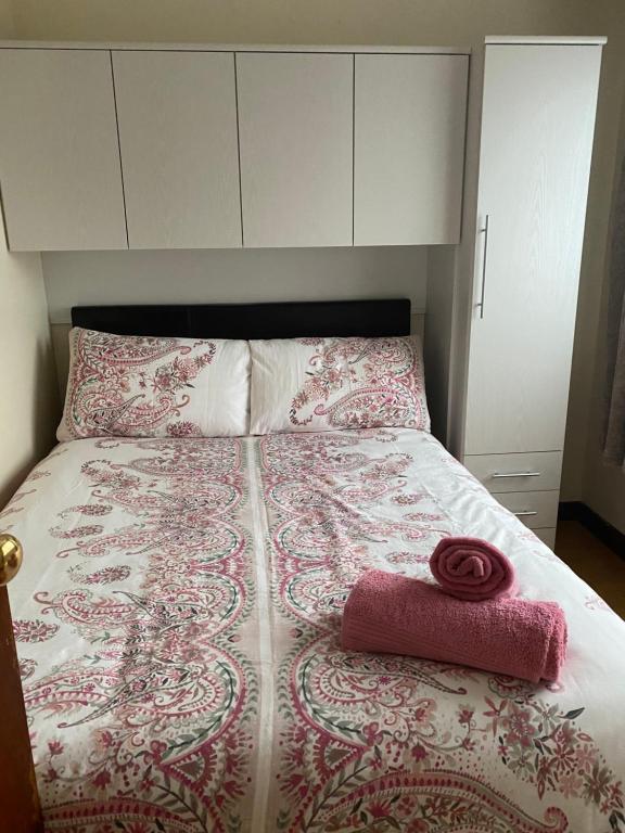 a bed with a pink and white comforter and a towel at Canal View in Belmullet