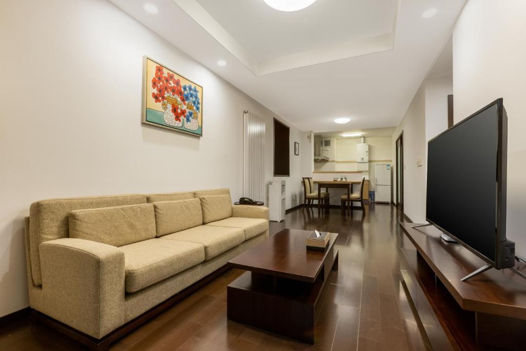 a living room with a couch and a flat screen tv at Belgravia Serviced Residence Wuxi in Wuxi