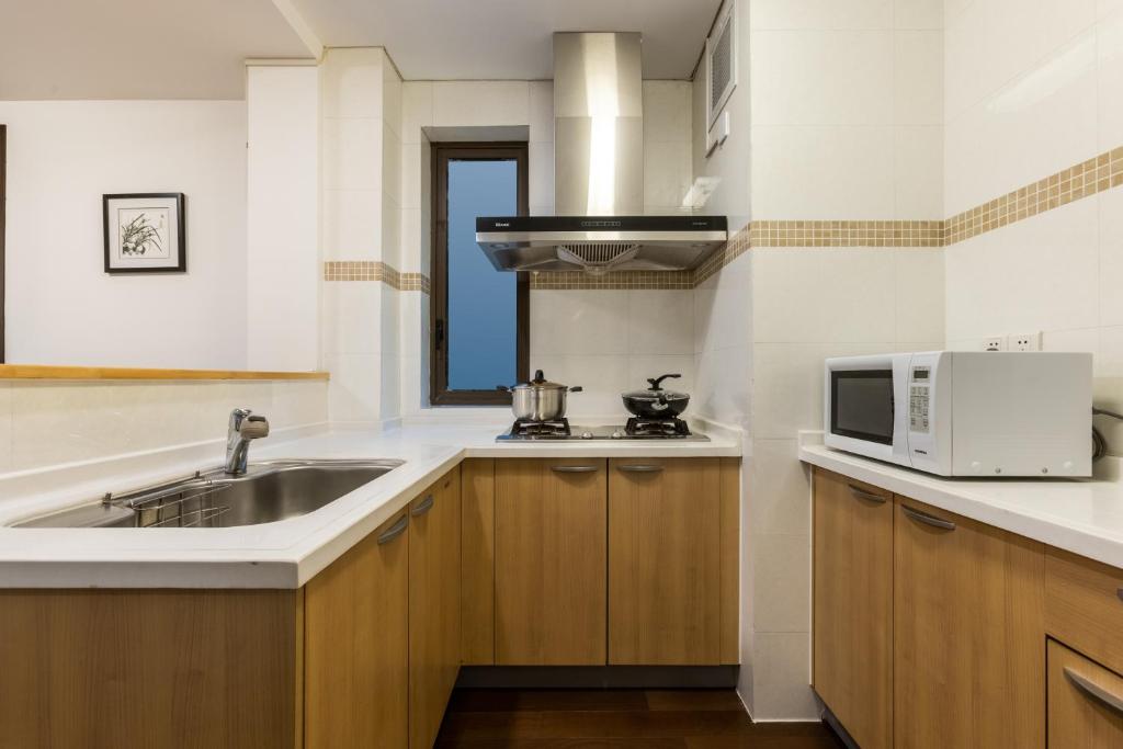 a kitchen with a sink and a microwave at Belgravia Serviced Residence Wuxi in Wuxi