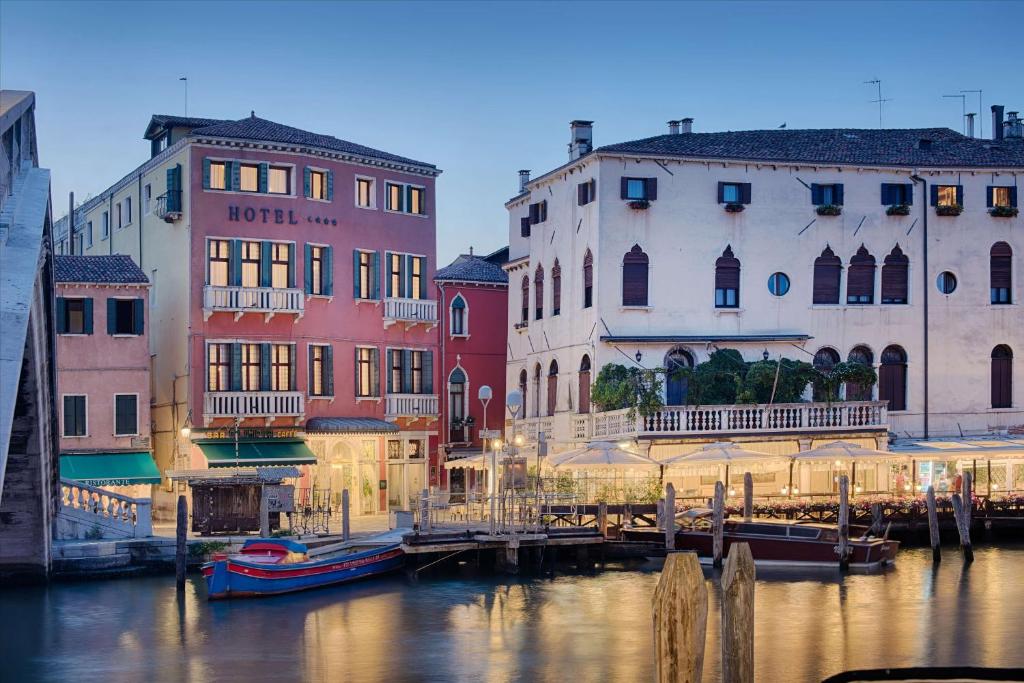 un gruppo di edifici vicino a un canale con barche di NH Venezia Santa Lucia a Venezia