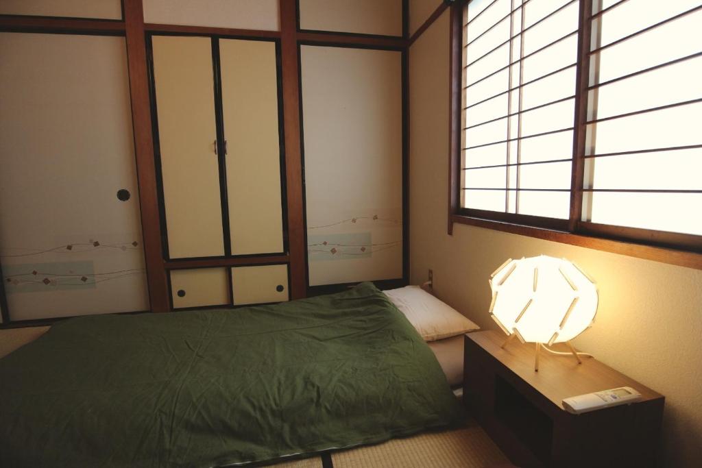 sypialnia z zielonym łóżkiem i lampką w obiekcie Hokuriku Saikawa Building No.2 Building 3 Floor / Vacation STAY 1944 w mieście Kanazawa