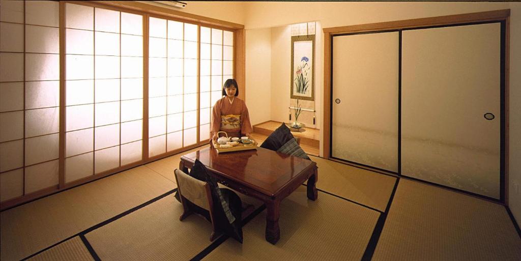 Shizuka Ryokan Japanese Country Spa & Wellness Retreat في هيبورن سبرينغز: امرأة تجلس على طاولة في غرفة