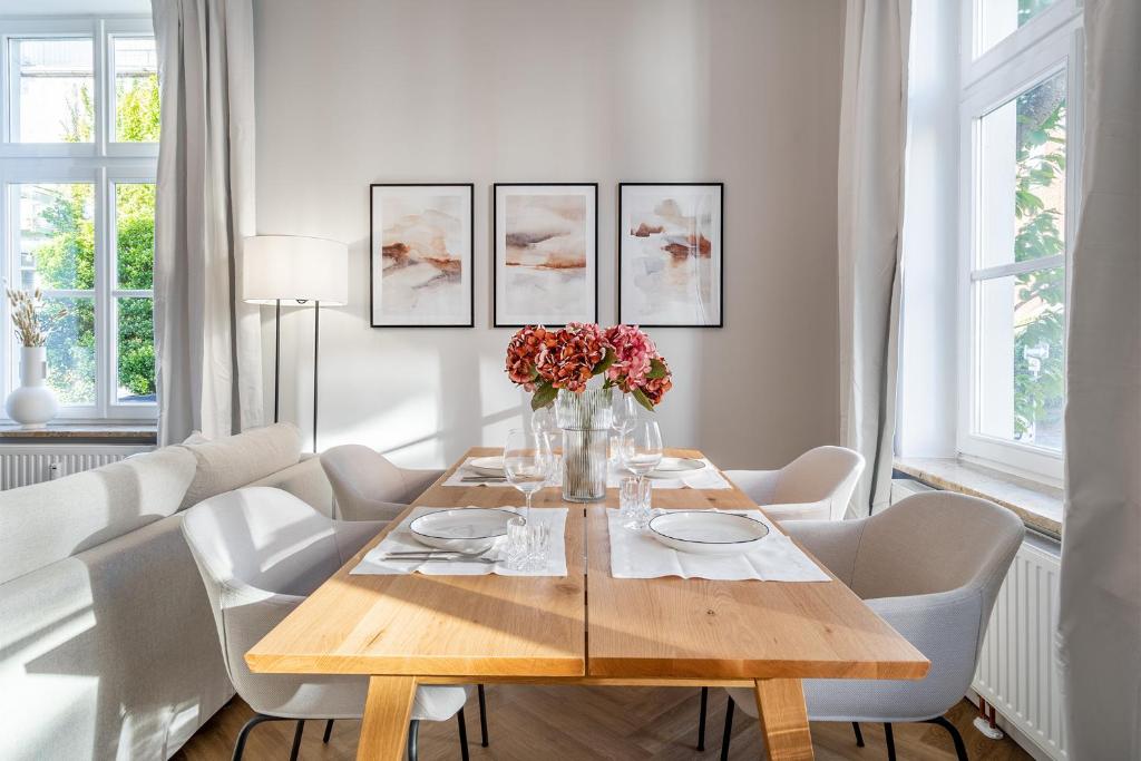ein Esszimmer mit einem Holztisch und weißen Stühlen in der Unterkunft Apartment Villa Anna - Wohnung mit Stellplatz in Emden