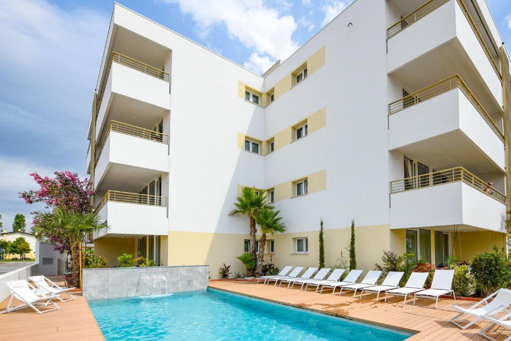 un immeuble d'appartements avec une piscine et des chaises longues dans l'établissement Residence Sunlight, à Lido di Jesolo