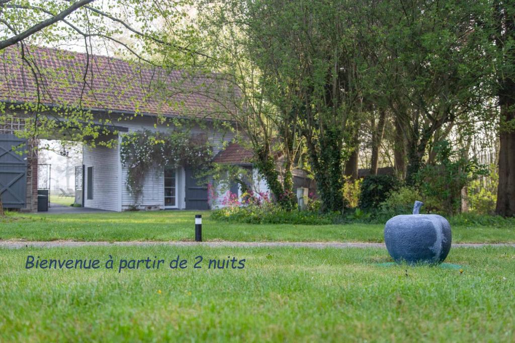 une grande citrouille bleue assise dans l'herbe devant une maison dans l'établissement La Pomme Pétillante, à Maisnières
