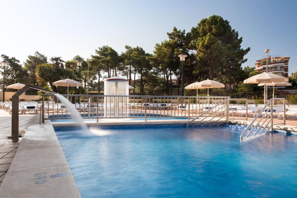 una piscina con una fuente y sombrillas en htop Royal Star & SPA #htopFun en Lloret de Mar