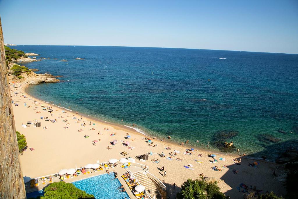 einen Blick über den Strand mit Menschen und Sonnenschirmen in der Unterkunft htop Caleta Palace #htopBliss in Platja  d'Aro