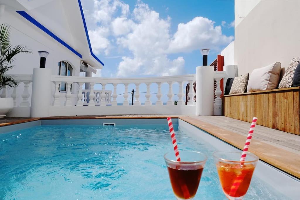 two drinks sitting on the edge of a swimming pool at Villa Beauregard in Sainte-Luce