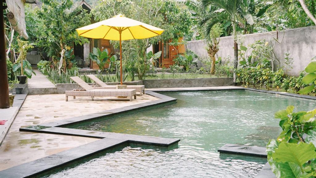 einen Pool mit Sonnenschirm und Stühlen im Hof in der Unterkunft Lullabi Lumbung Villa in Lajor
