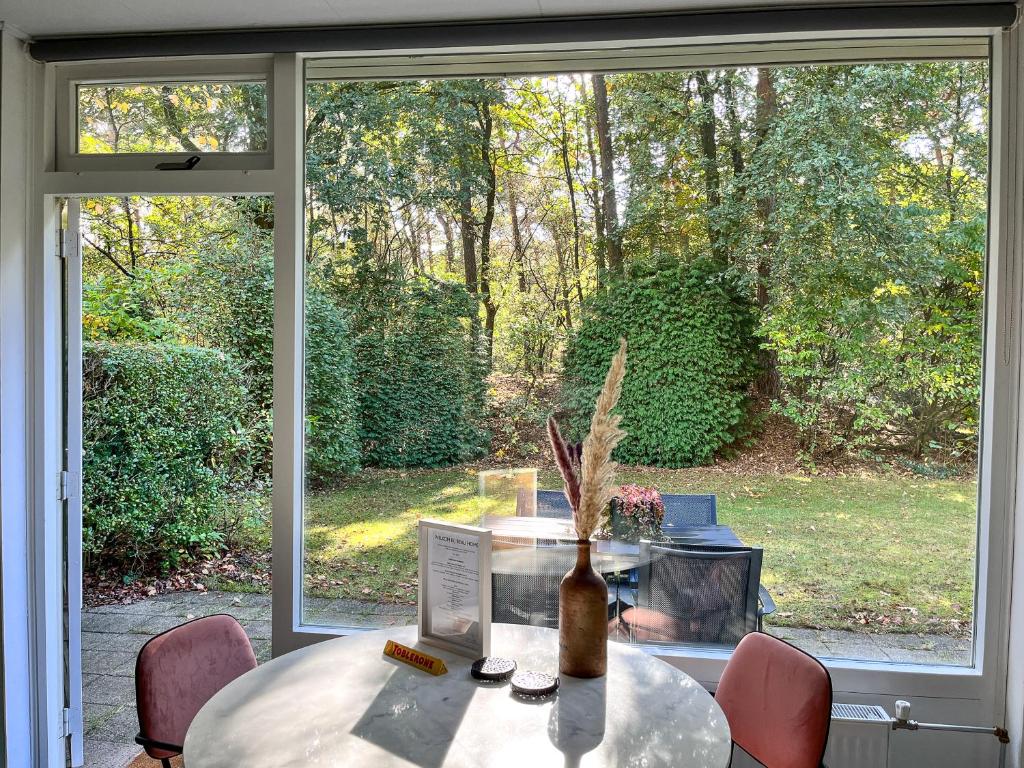 une table avec un vase devant une fenêtre dans l'établissement Modern natuurhuisje midden in het bos op de Veluwe - Beau Home, à Otterlo