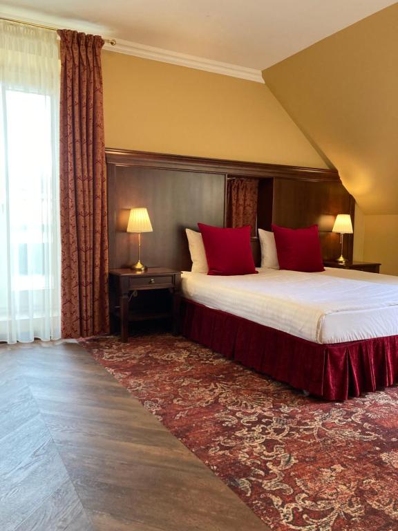 a bedroom with a large bed with red pillows at Guest House Pirklių Namai in Klaipėda