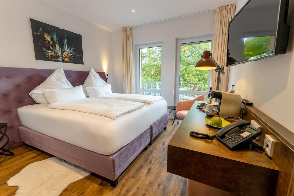 a hotel room with a bed and a desk with a phone at Landhaus Biewald in Göttingen