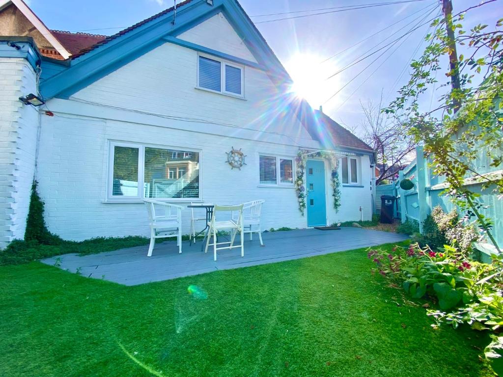 Casa blanca con mesa y sillas en el patio en 5 Min Walk to the Best Beach! Lovely 3 Bedroom Charming Cottage! - Great Location - FREE Parking - Fast WiFi - Smart TV - sleeps up to 6! Close to Bournemouth & Poole Town Centre & Sandbanks, en Bournemouth