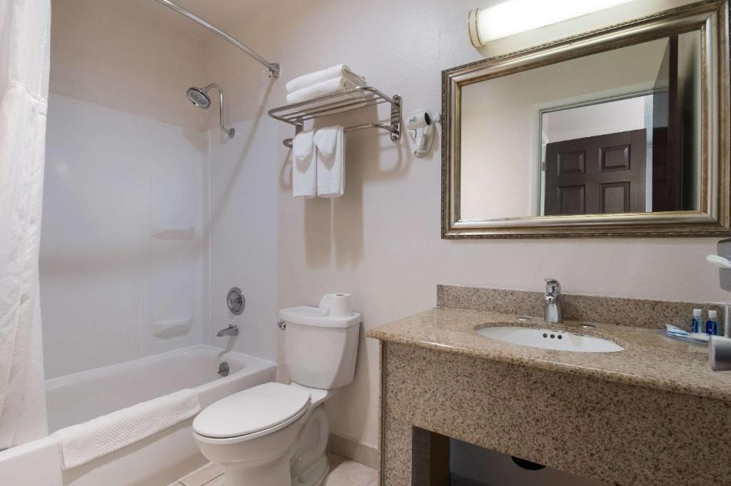 a bathroom with a toilet and a sink and a mirror at Rodeway Inn & Suites Hwy 217 & 26 W in Portland