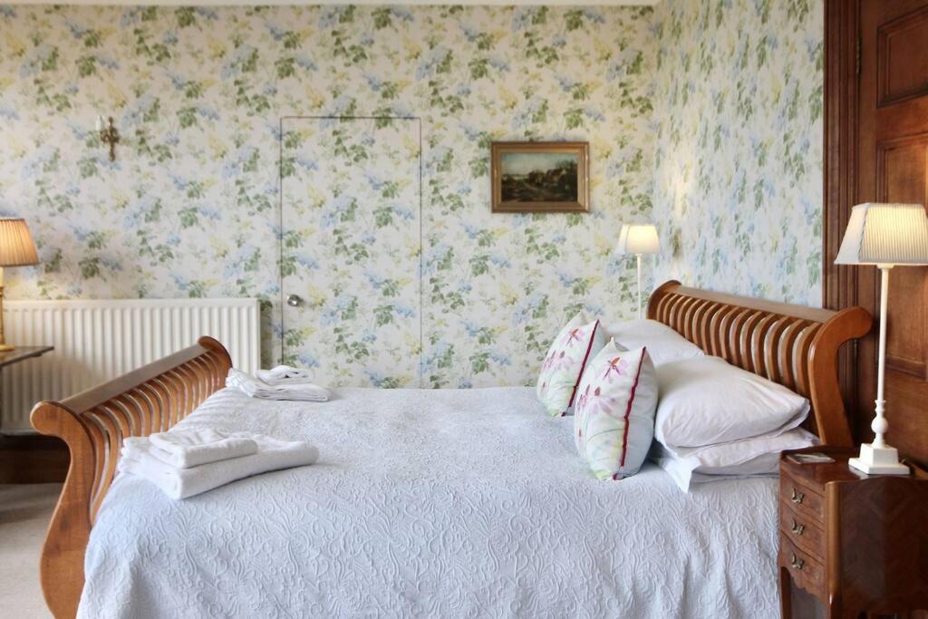 a bedroom with a bed with white sheets and floral wallpaper at Glen Hill in Deal