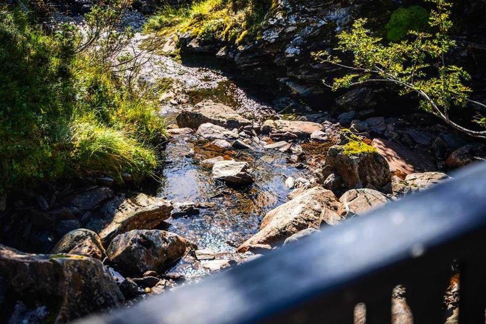 a stream of water with rocks on a bridge at Voss Waterfalls - Private mountain cabin & Traveller Award Winner! in Vossevangen
