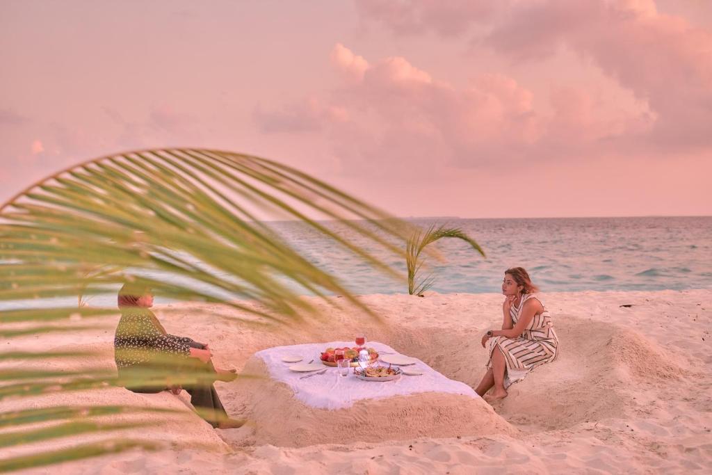 a woman sitting on a table on the beach at Splendour Grand in Maalhos