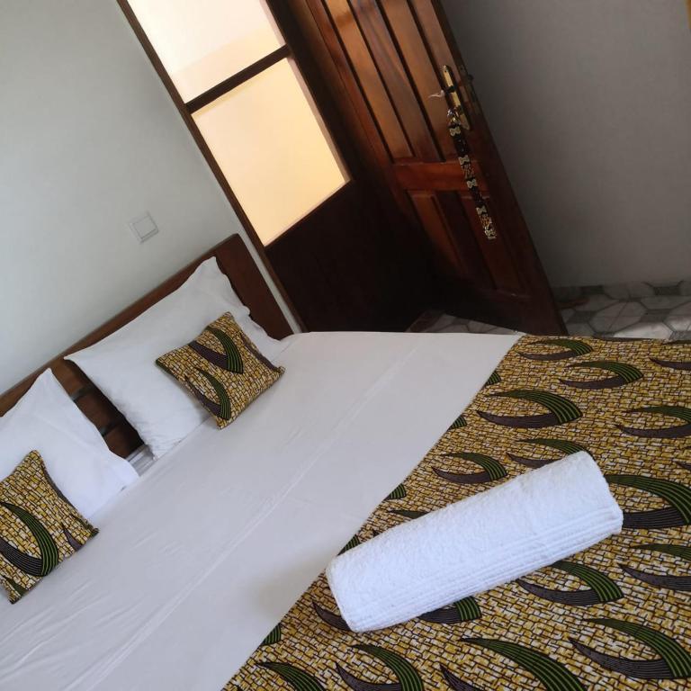 a bed with white sheets and pillows in a room at Micaval Residential in São Tomé