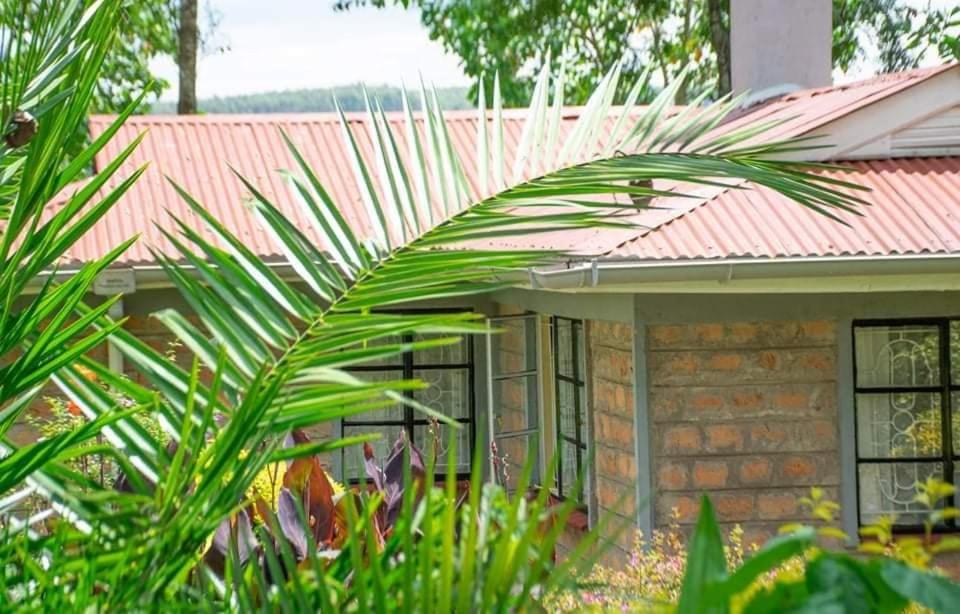 une maison avec un toit rouge et des plantes devant elle dans l'établissement Zoe Homes 1br and 2br Cottage own compound -Kericho town near Green Square mall, à Kericho