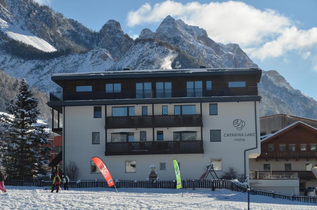 a building in the snow with mountains in the background at Residence Catarina Lanz in San Vigilio Di Marebbe