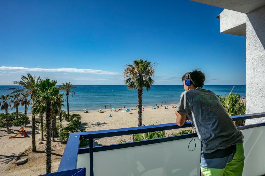 カンブリルスにあるPins Platja Apartmentsの海岸を見下ろすバルコニーに立つ男