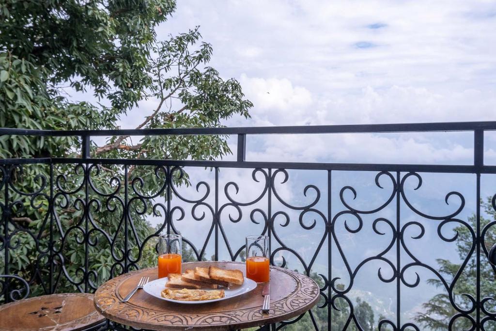 Una mesa con un plato de comida y dos vasos de jugo de naranja. en StayVista at Slice of Heaven, en Mussoorie