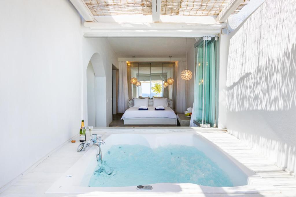 a bath tub in a room with a bedroom at Poseidon Blue Gastronomy Hotel in Afiartis