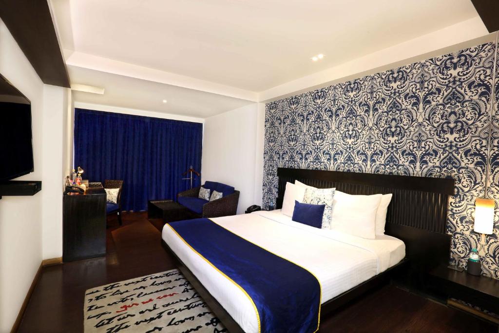 1 dormitorio con 1 cama con papel pintado azul y blanco en Mosaic Hotel, Noida en Noida