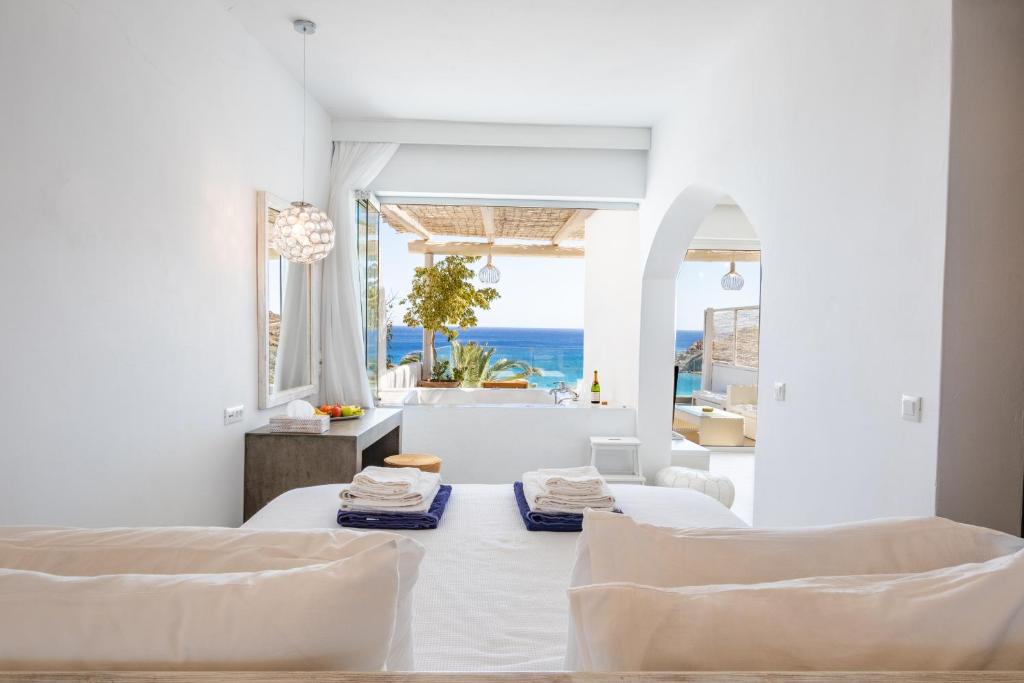 a white room with two beds and a view of the ocean at Poseidon Blue Gastronomy Hotel in Afiartis