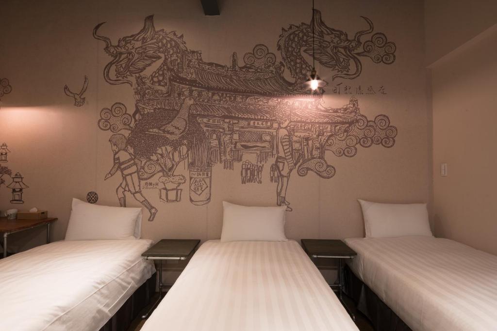 two beds in a room with a mural on the wall at Cho Hotel in Taipei