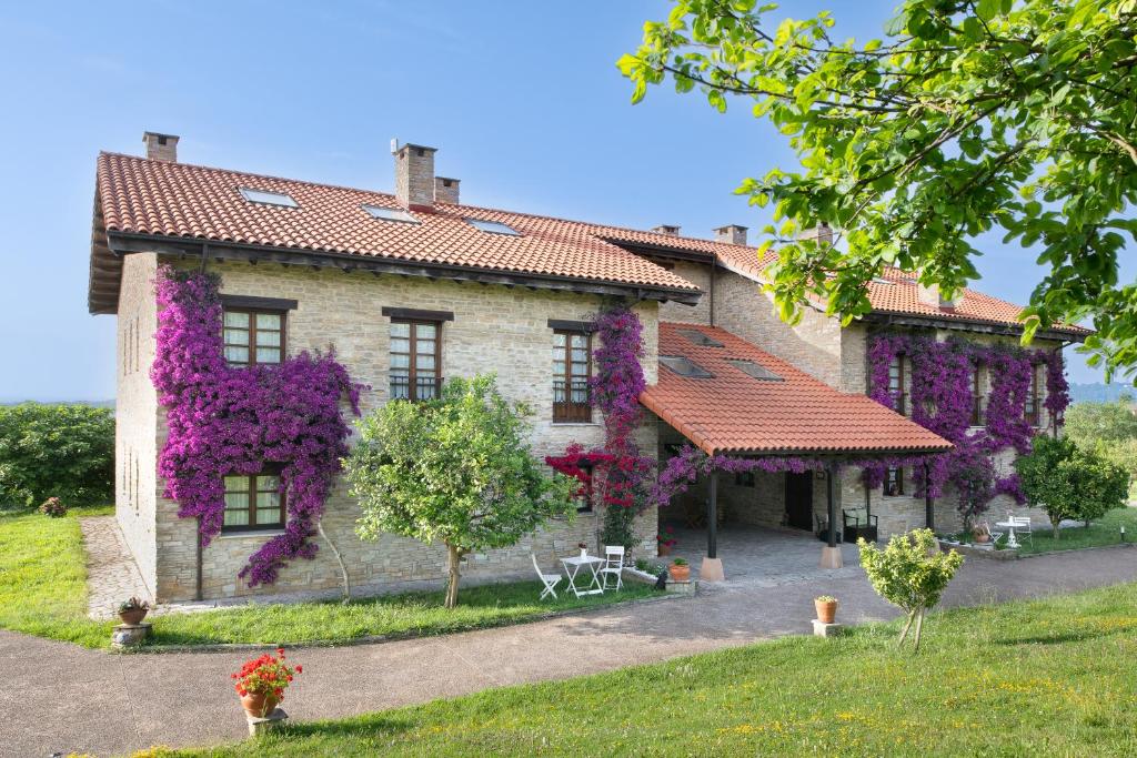 Una casa con flores púrpuras a un lado. en Hotel Rural Casona de Cefontes, en Cefontes