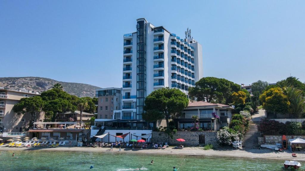 a tall building on a beach next to the water at SIGNATURE BLUE RESORT in Kusadası