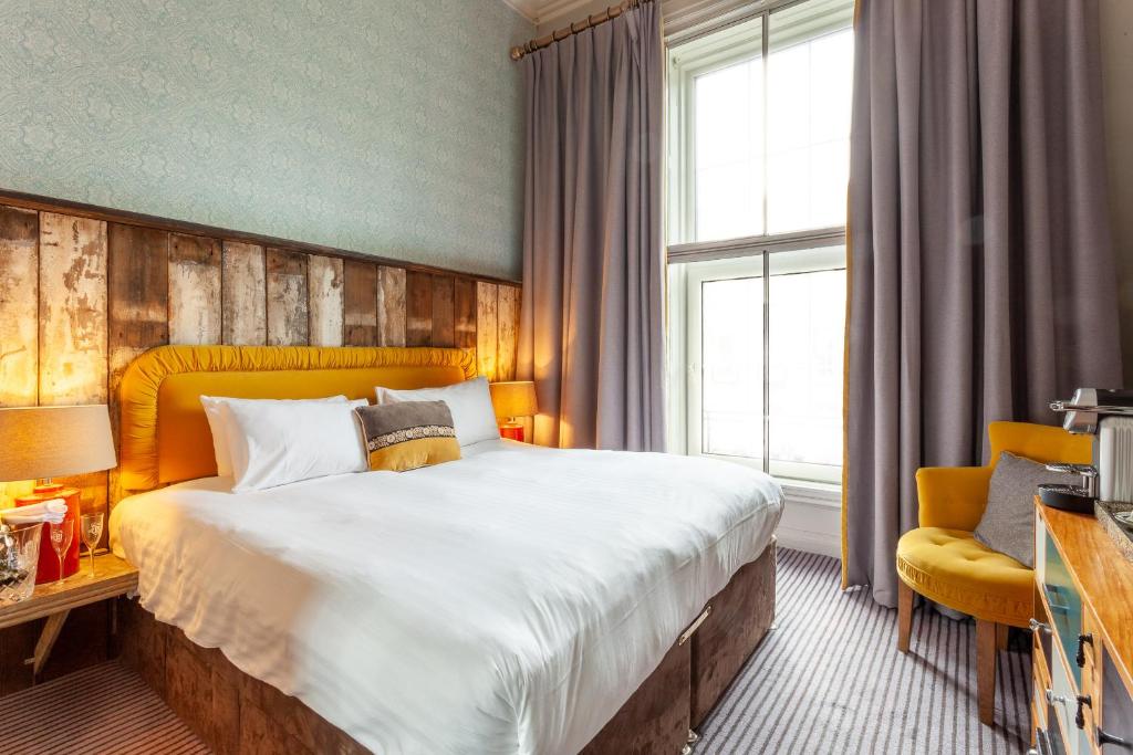 een hotelkamer met een groot bed en een stoel bij House Bedrooms Dublin in Dublin