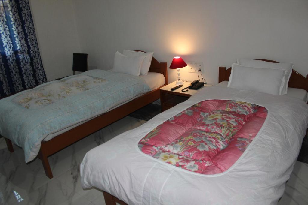 a bedroom with two beds and a lamp on a table at HOTEL BODHGAYA INN in Bodh Gaya