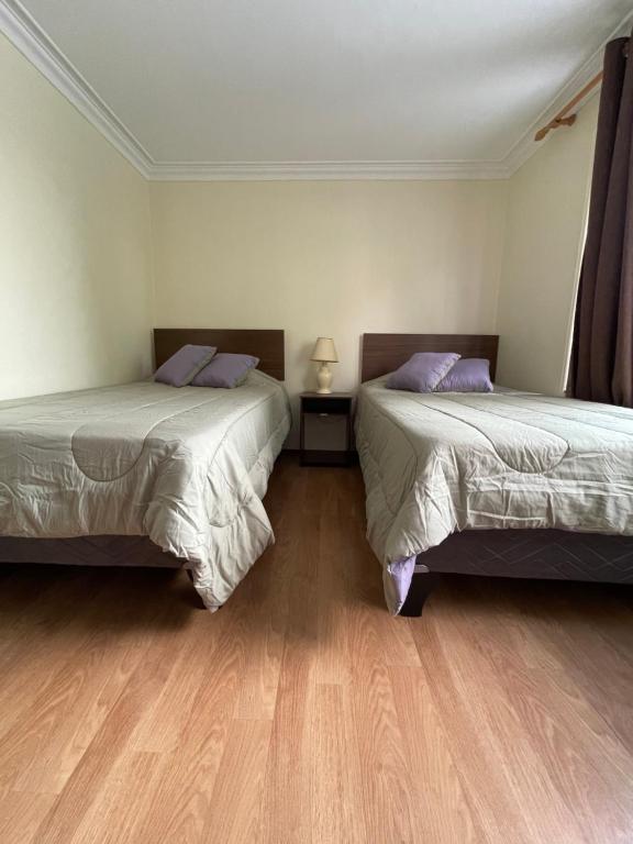 twee bedden in een kamer met houten vloeren bij El Centrito in Talca