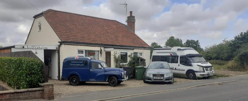 two trucks and a car parked in front of a house at Littleholme in Potter Heigham
