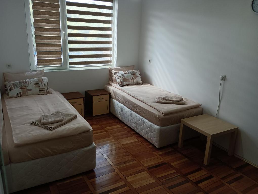 Cette chambre comprend 2 lits, une table et une fenêtre. dans l'établissement Апартамент Ели, à Veliko Tarnovo