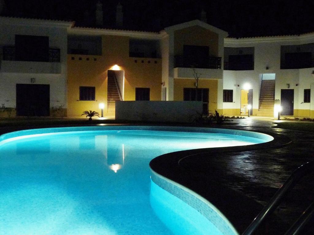 a swimming pool in front of a building at night at Sagres Time Apartamentos in Sagres