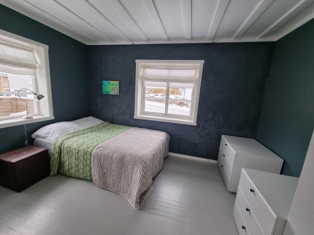 a small bedroom with a bed and two windows at Koselig leilighet midt i sentrum in Skjervøy
