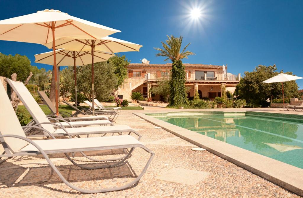 a pool with chairs and umbrellas next to a building at Agroturismo Son Burgues in Petra