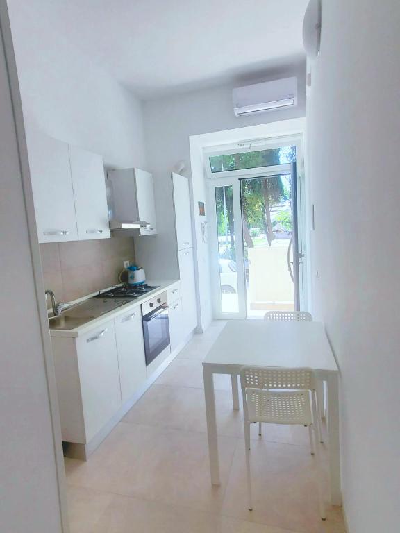 a kitchen with a white table and chairs and a table and a kitchen at B&B Lido Apartament 10B in Civitanova Marche