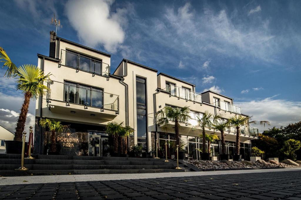 a white building with palm trees in front of it at POŁUDNIK PARK Boutique Hotel Conference&SPA in Stargard