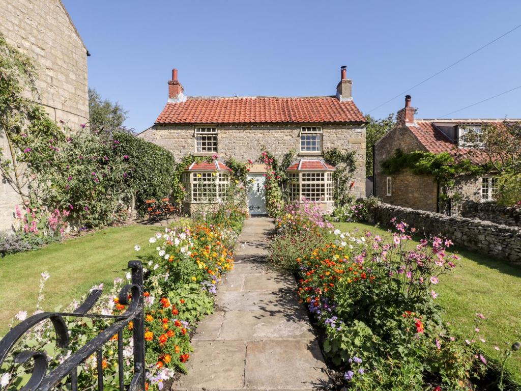 an old stone house with a garden of flowers at Bute Cottage in Pickering